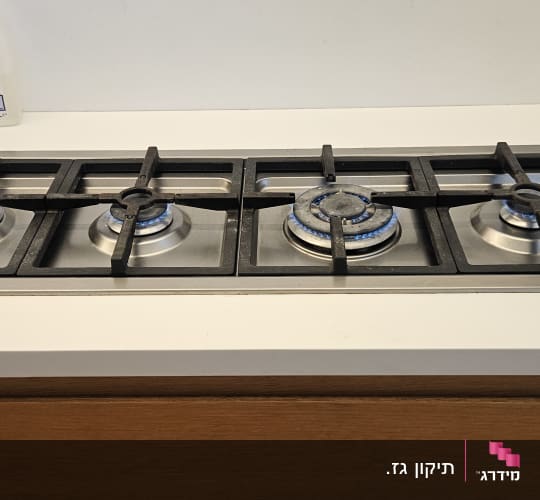 כיריים גז עם להבות דולקות על משטח מטבח